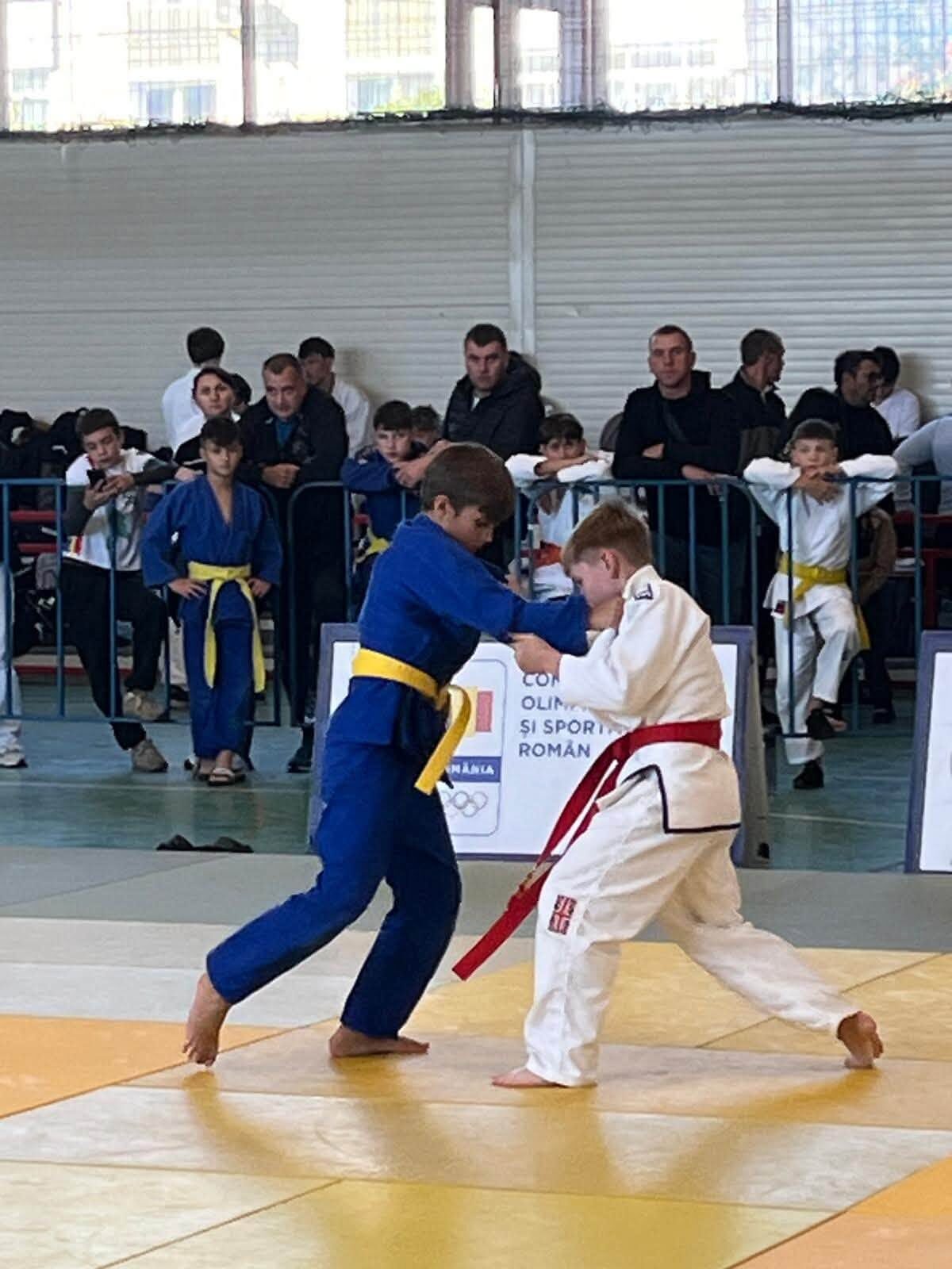 Copil în kimono albastru și copil în kimono alb cu centură roșie, într-un schimb pe saltea